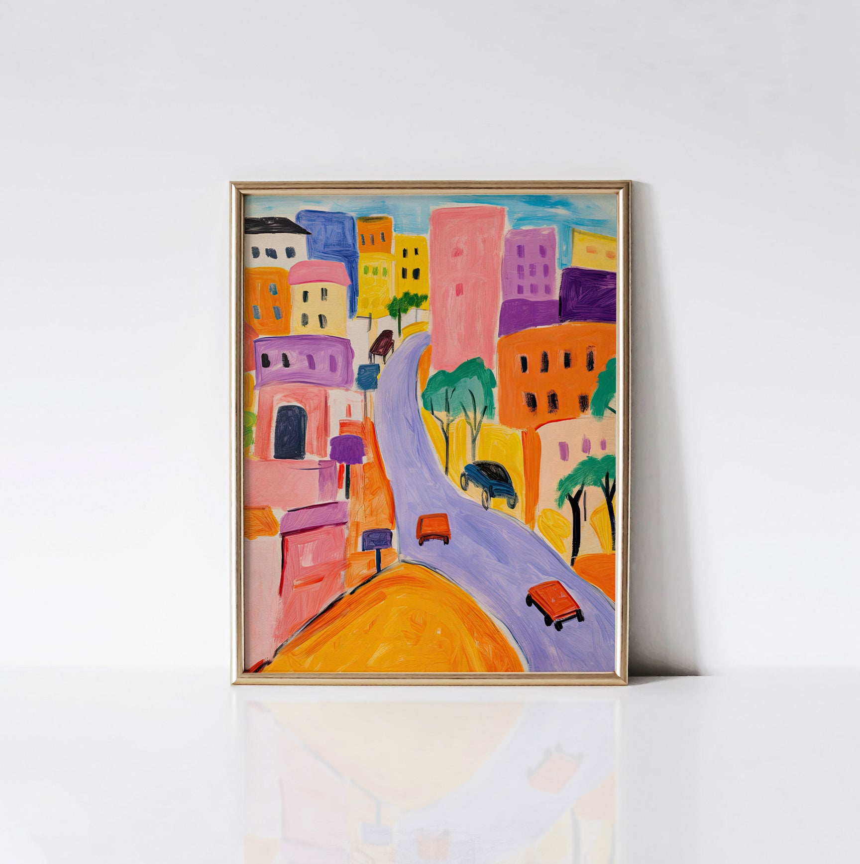 Vibrant Cityscape art print displayed in a sleek gold frame, featuring a lively city scene with bold buildings, winding streets, and colorful vehicles