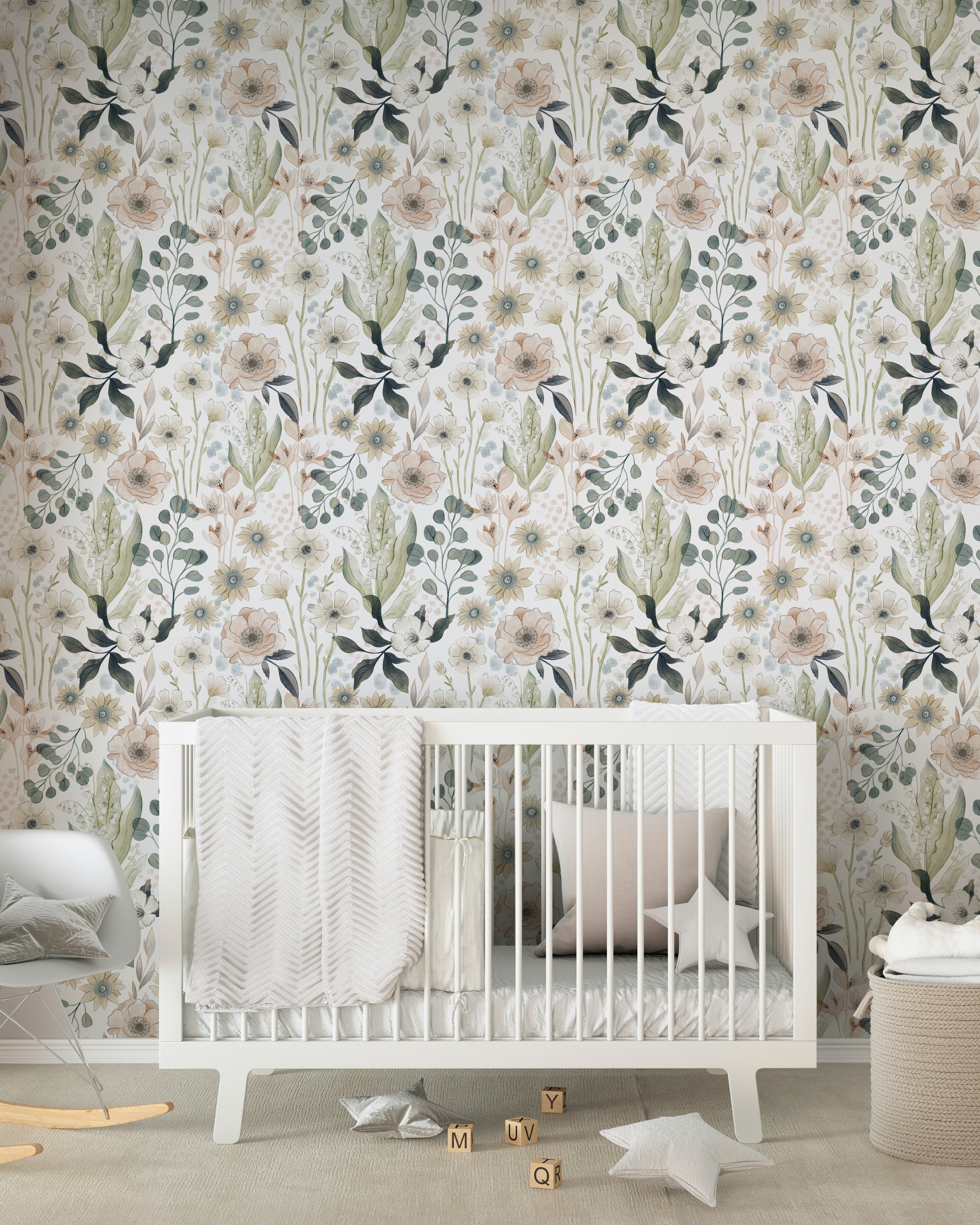 A cozy nursery room featuring a floral wallpaper with a design of large and small flowers in shades of beige, cream, blue, and green. The room includes a white crib with a soft gray blanket and a pillow, wooden blocks on the floor, and a round storage basket nearby.