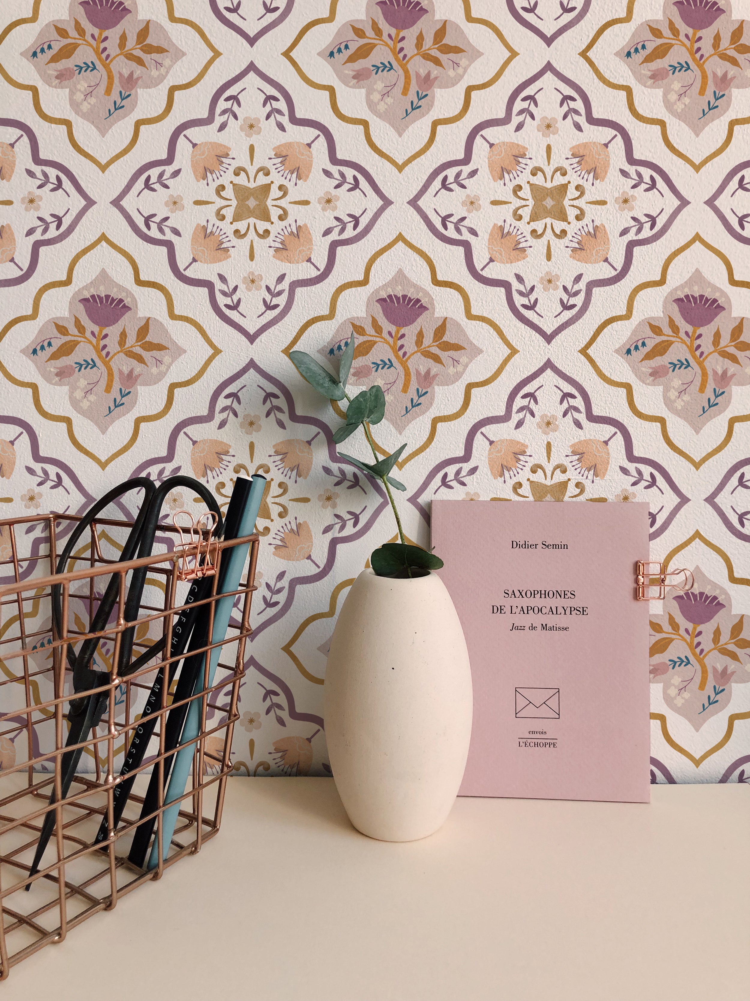 Home office setup with Moroccan Floral Tile Wallpaper in the background, showcasing a decorative setup with books, a vase, and office supplies.