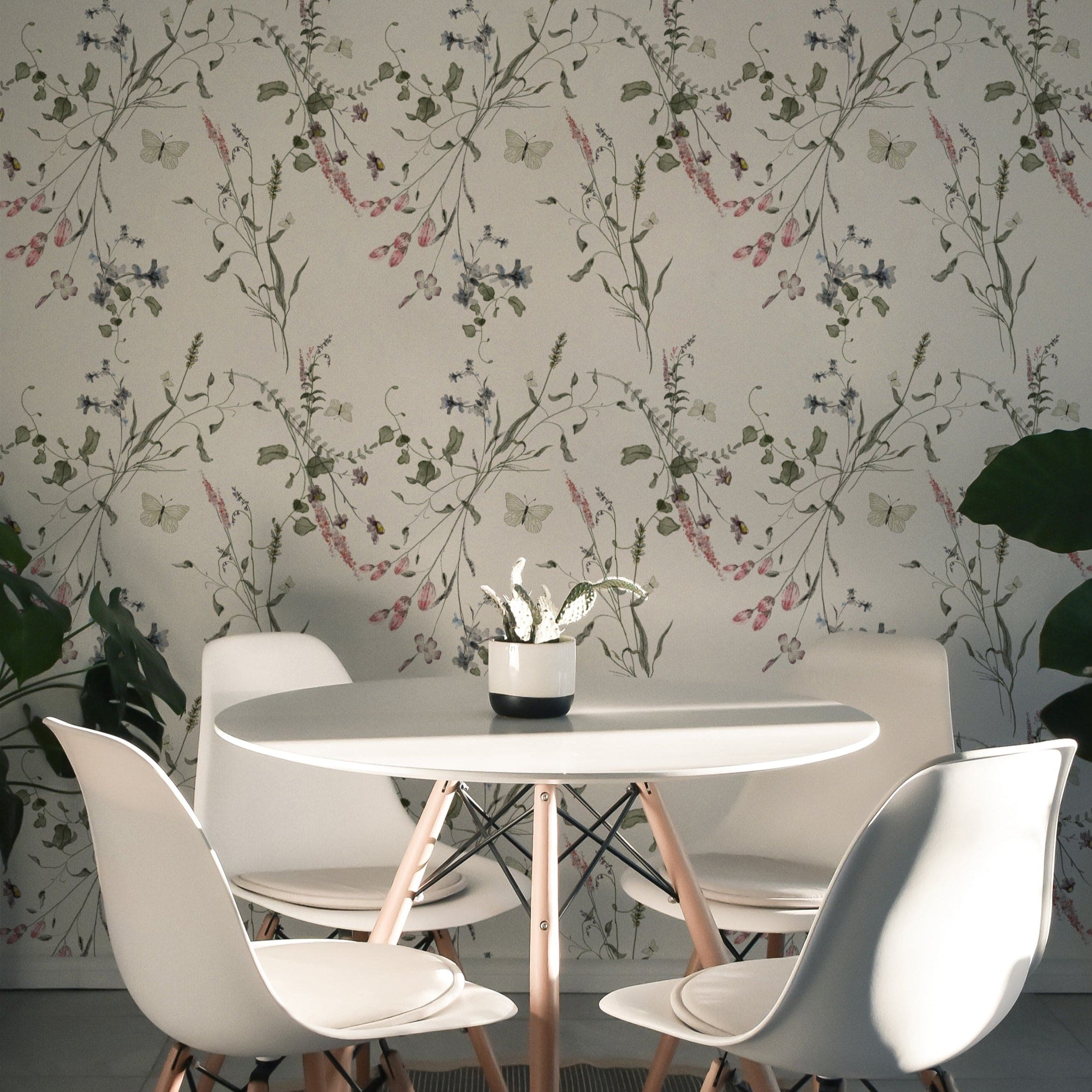 A modern dining area adorned with the Lovely Botanicals Wallpaper, which brings a fresh, natural vibe to the space. The light floral patterns provide a soft background for the sleek white table and chairs, enhancing the room’s contemporary aesthetic.