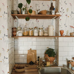 Rustic kitchen with Dainty Botanicals wallpaper enhancing a cozy corner filled with wooden shelves, assorted jars, and green houseplants against a backdrop of floral and botanical illustrations