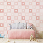 A children's play area featuring Coralie Wallpaper in Dusty Pink, with a pattern of light pink squares and darker pink starburst motifs, creating a lively and soft ambiance perfect for a playful environment.