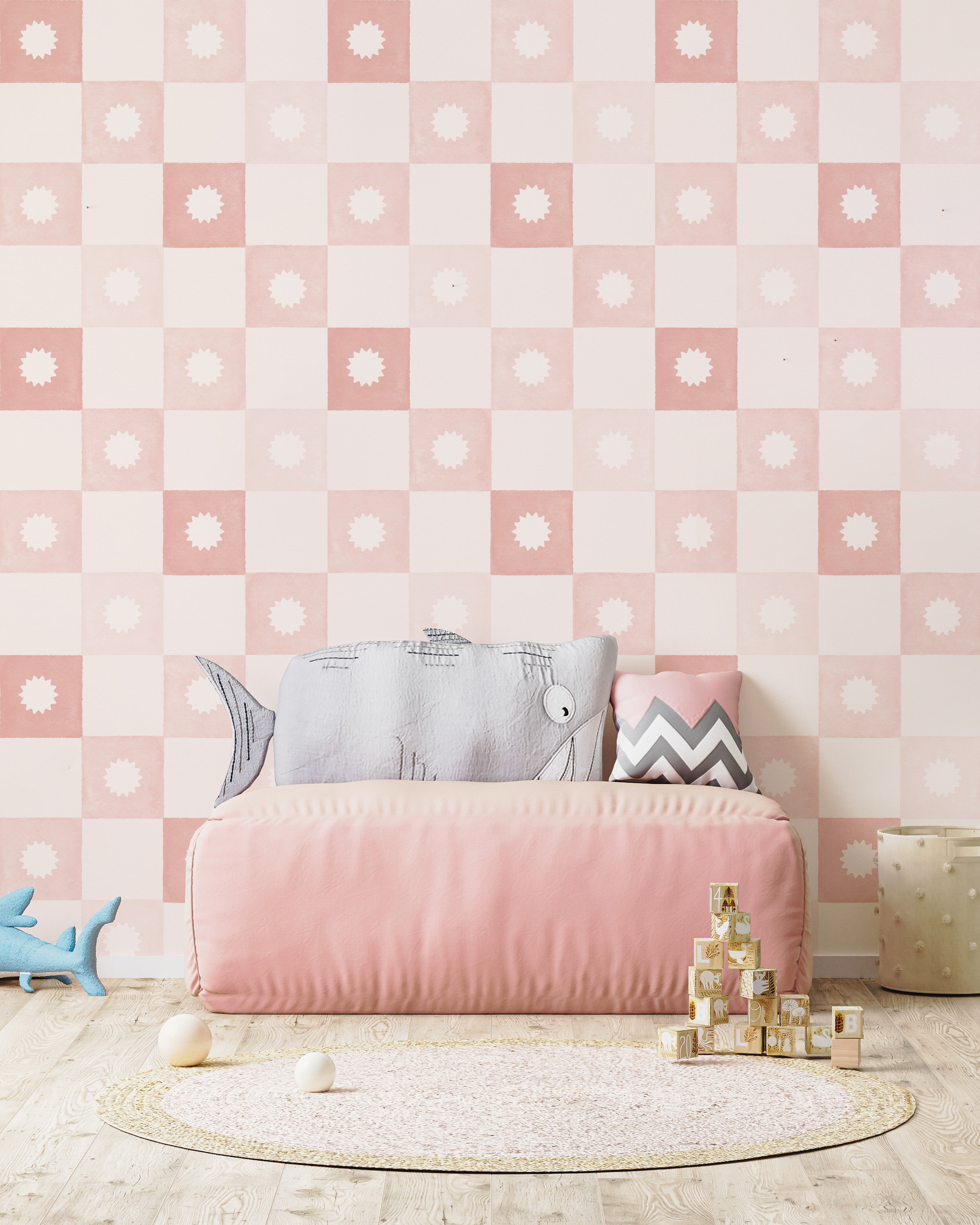 A children's play area featuring Coralie Wallpaper in Dusty Pink, with a pattern of light pink squares and darker pink starburst motifs, creating a lively and soft ambiance perfect for a playful environment.