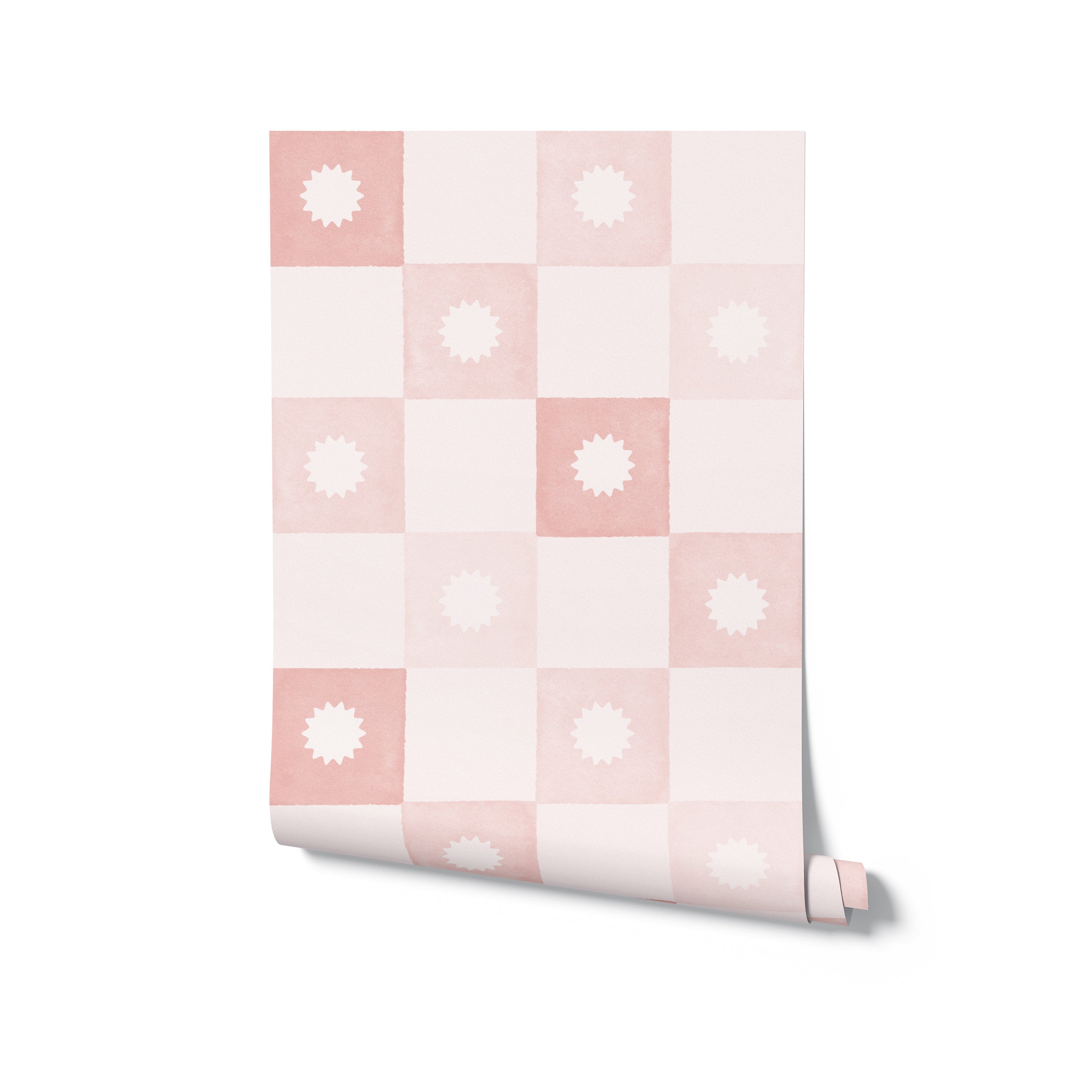 A roll of Coralie Wallpaper in Dusty Pink unrolled slightly to show off its distinctive checkered pattern with delicate starburst designs in each square, perfect for adding a playful yet sophisticated touch to interior spaces.