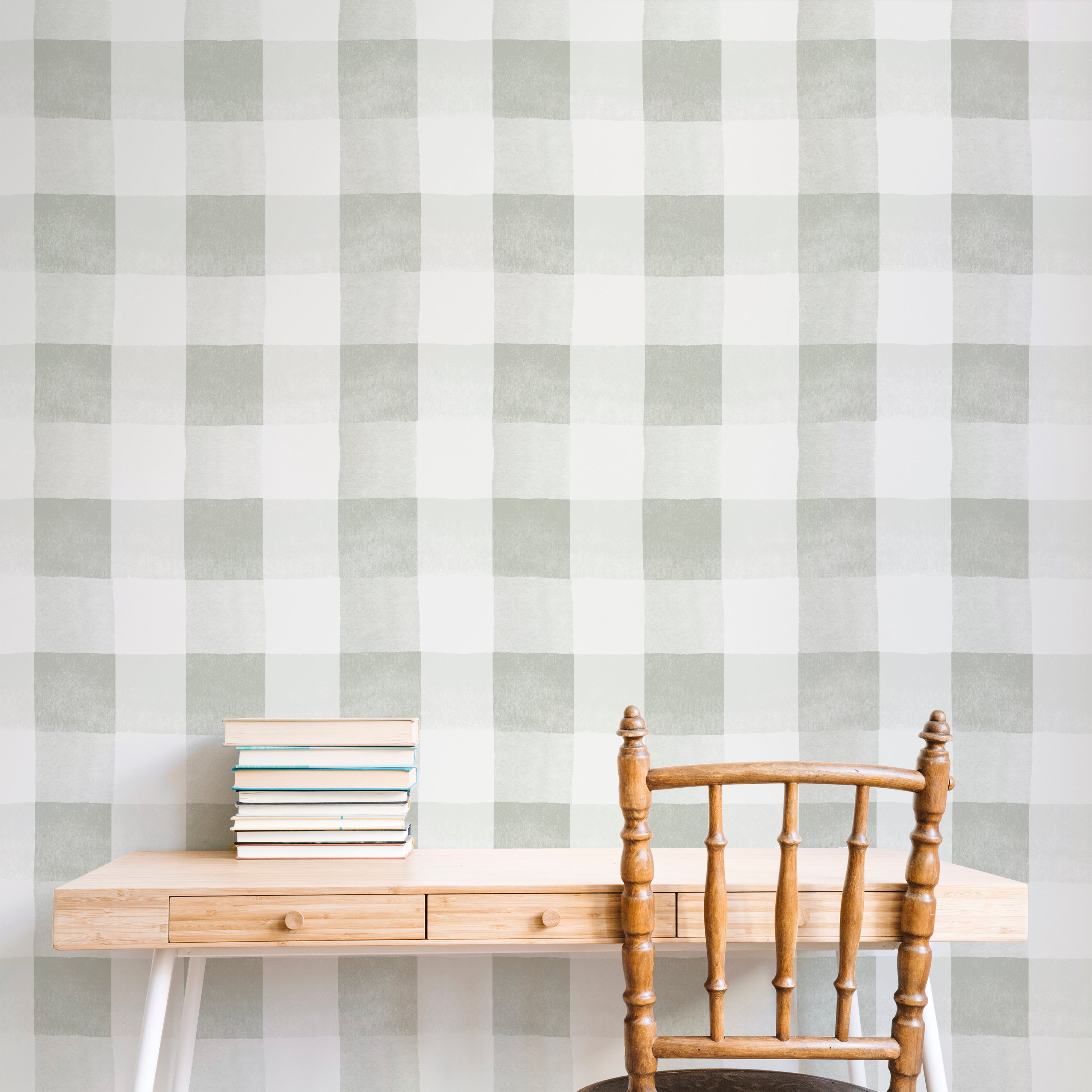 A square image of a home office area showcasing the Camille Wallpaper - Olive as a backdrop. The space is furnished with a natural wood desk and a traditional spindle-back chair, complementing the olive green and white checkered pattern of the wallpaper, which adds a cozy, yet contemporary vibe to the room.