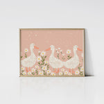 Daisy Ducks Art Print framed in an elegant gold frame, showcasing three charming white ducks with orange beaks and feet among white daisies on a soft pink background