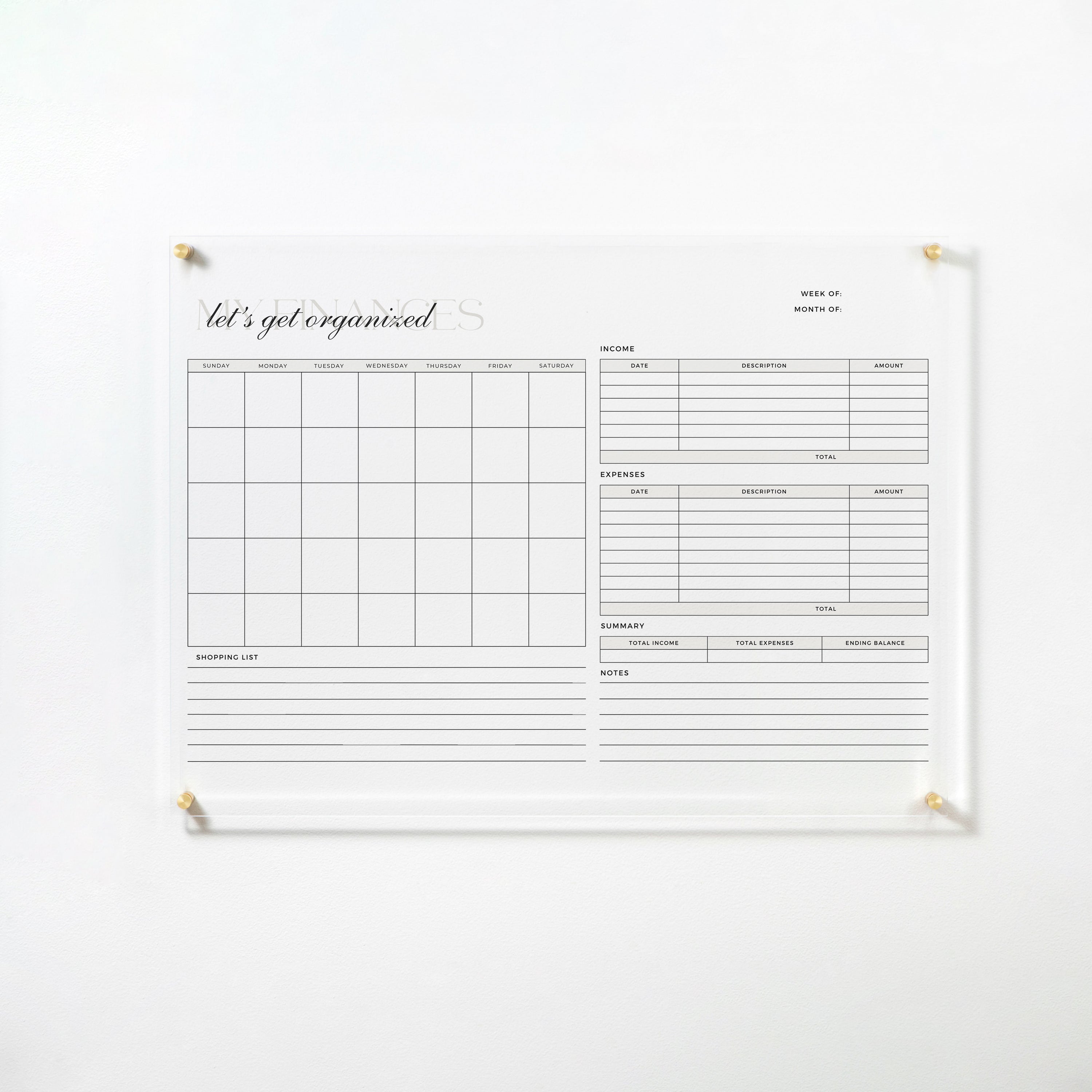 The full view of the same acrylic board, mounted on a white wall with gold pins. The board includes a monthly calendar, sections for tracking income and expenses, a summary area, and notes section, designed to help organize finances efficiently.
