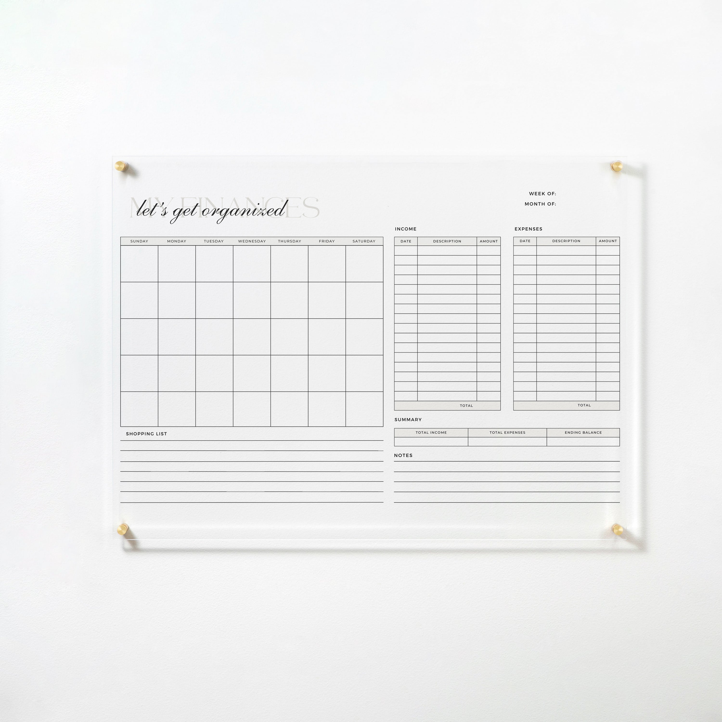 The full view of the same acrylic board, mounted on a white wall with gold pins. The board includes a monthly calendar, columns for income and expenses, a summary section, shopping list, and notes area, making it an ideal tool for financial organization.