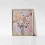 Spring Garden Bouquet Art Print displayed in a gold frame against a white wall, highlighting the vivid colors and detailed brush strokes of the floral arrangement in the glass vase.