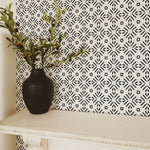 Elegant entryway decorated with Geometric Wallpaper III - Black, featuring a black vase with greenery against the striking black and white patterned wallpaper