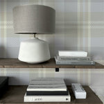 Close-up view of a shelf styled against Heirloom Tartan Plaid Wallpaper, displaying a lamp and books. The wallpaper's neutral tartan pattern adds a subtle yet elegant touch to the decor