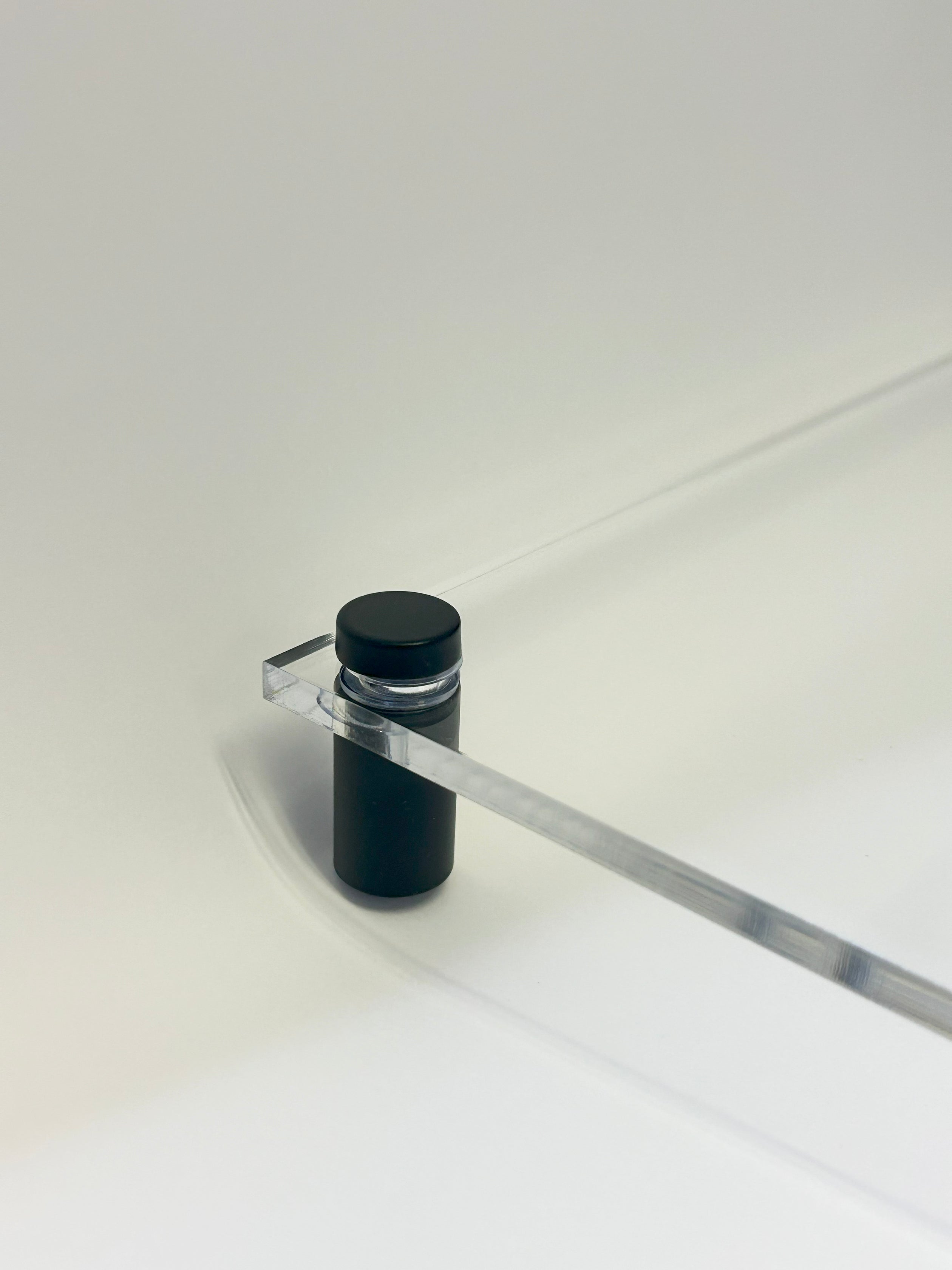 Close-up of a black cylindrical mount holding a transparent acrylic board, demonstrating the sturdy support and sleek design.