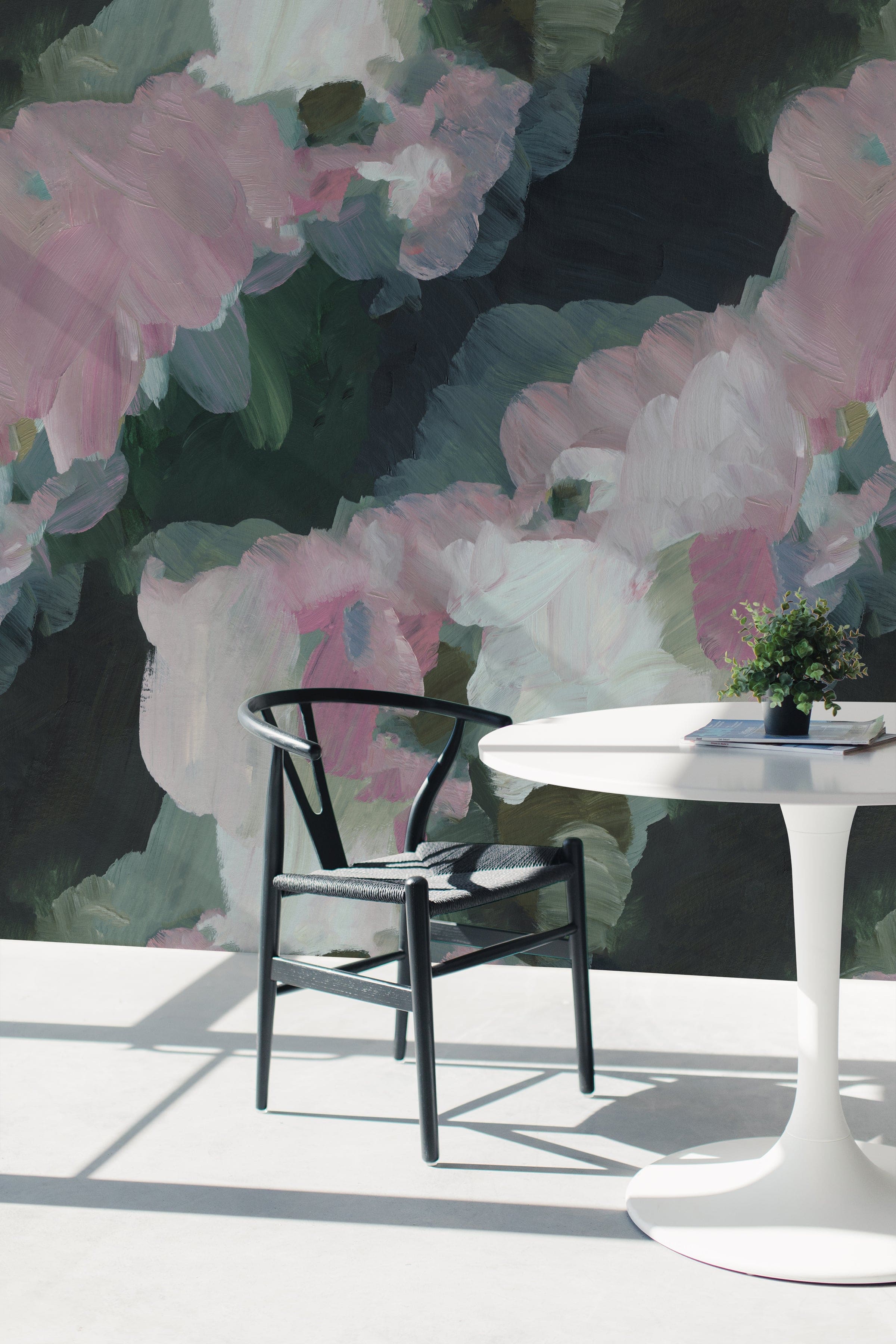 A modern room setting enhanced by the Brushed Harmony Wallpaper, showing a spacious area with a minimalist white table and a contemporary black chair. The wallpaper's abstract floral pattern in soft pinks and greens adds a touch of artistic flair to the decor.