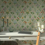 A modern kitchen setting with a wallpaper that showcases an extensive variety of garden flowers on a light background. The detailed pattern includes several species in full bloom, creating a dynamic and enchanting wall feature that enhances the natural light of the room.