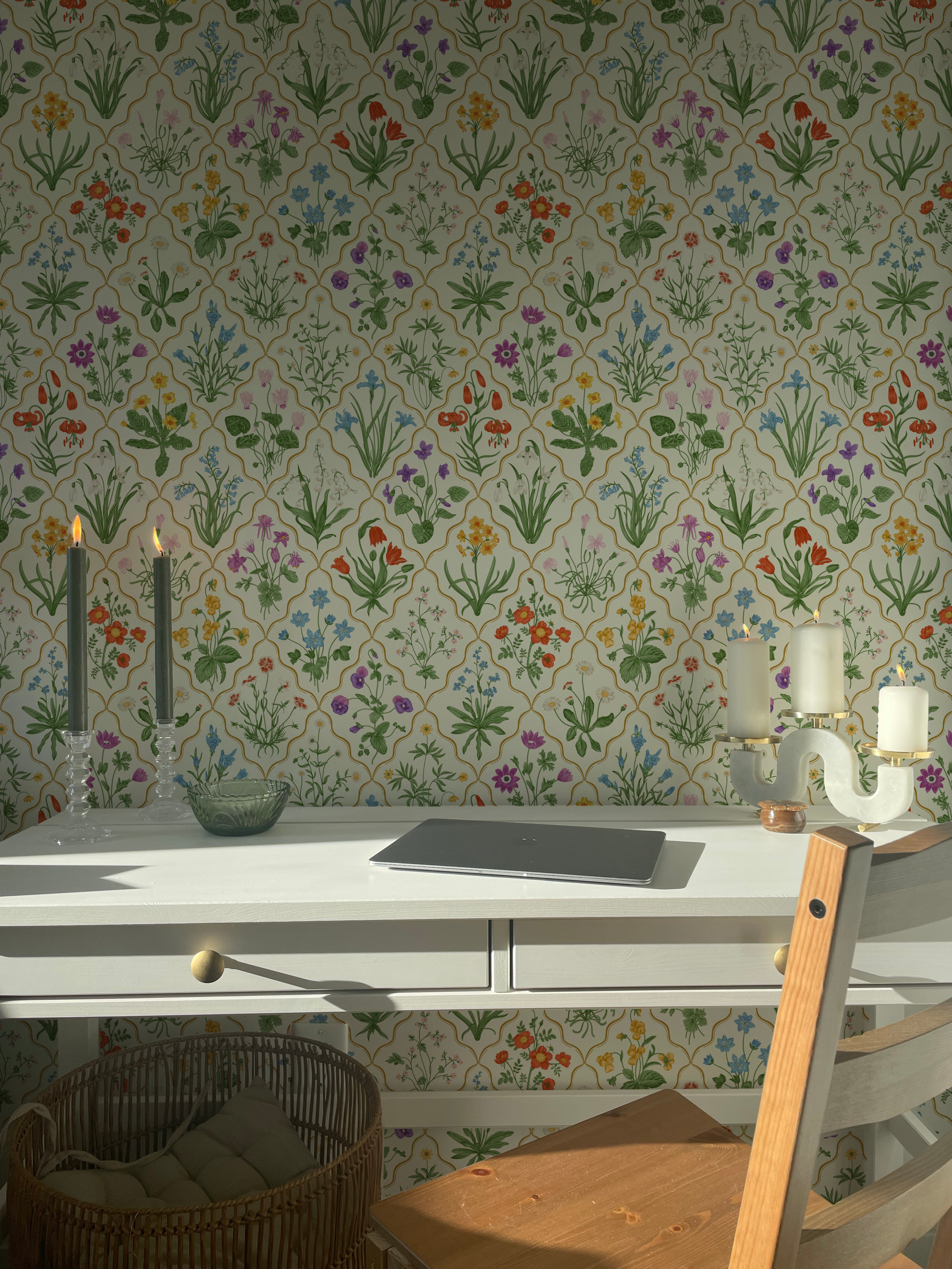 A modern kitchen setting with a wallpaper that showcases an extensive variety of garden flowers on a light background. The detailed pattern includes several species in full bloom, creating a dynamic and enchanting wall feature that enhances the natural light of the room.