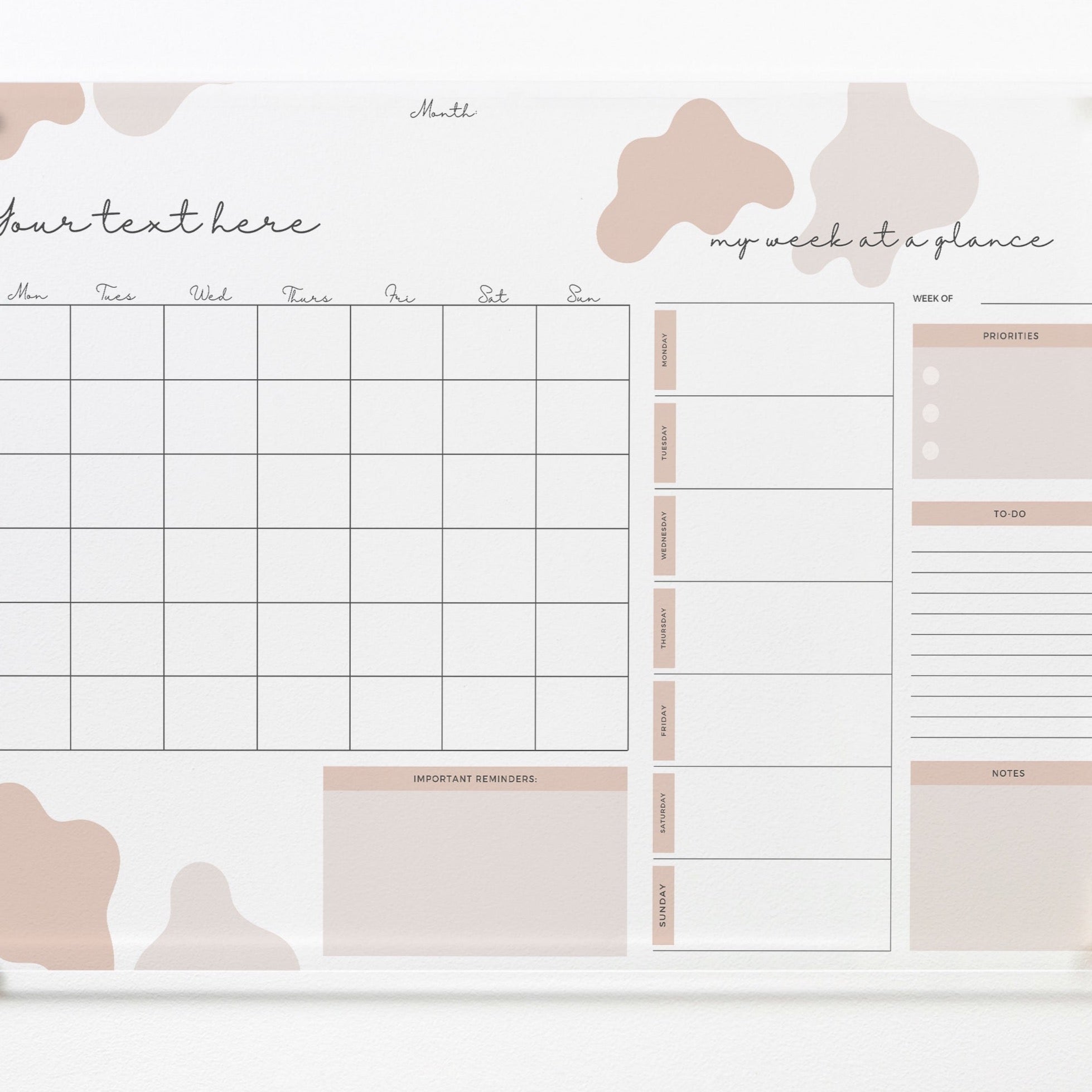 The "Custom Weekly Monthly Planner - Cute in Pink" dry erase acrylic board mounted on a wall with gold pins. It features a monthly calendar grid, sections for weekly planning, priorities, to-dos, notes, and important reminders. The board is decorated with whimsical pink and beige shapes, providing a cute and functional planning tool.