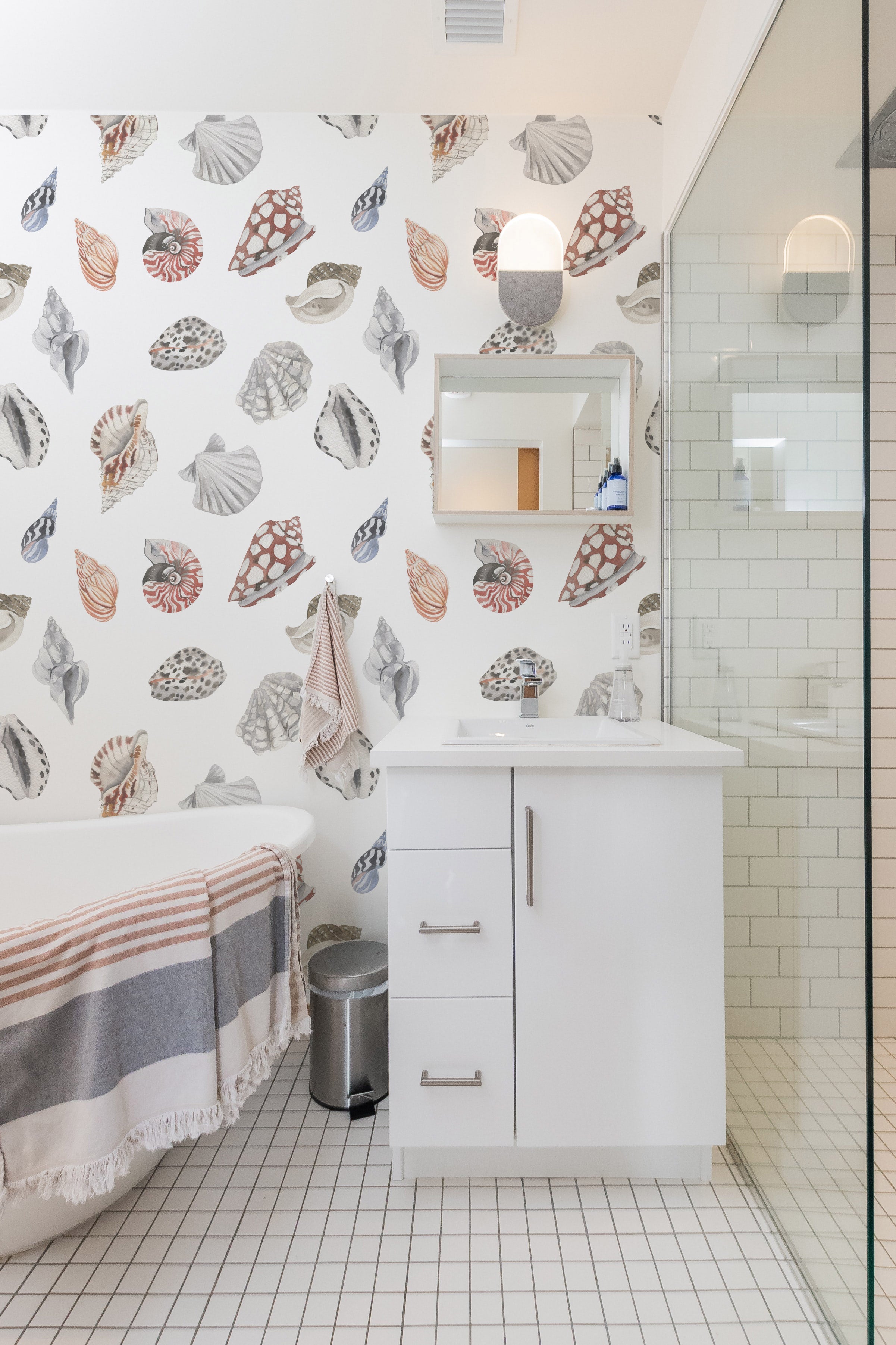 Elegant coastal bathroom with watercolor seashell wallpaper and white fixtures