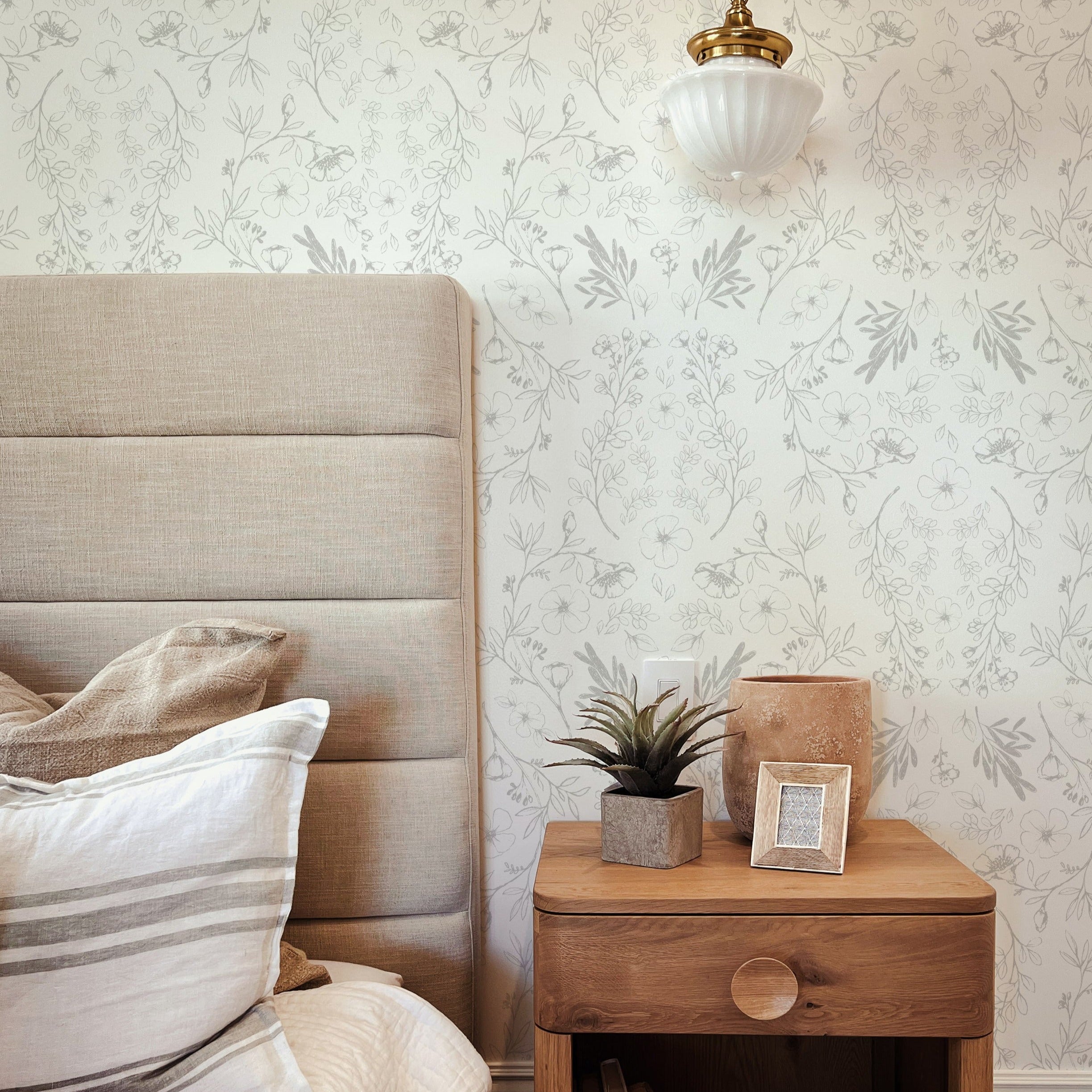 A cozy bedroom corner featuring Rustic Vintage Floral wallpaper, providing a soft, vintage aesthetic that complements the plush bedding and wooden bedside accessories for a tranquil ambiance.