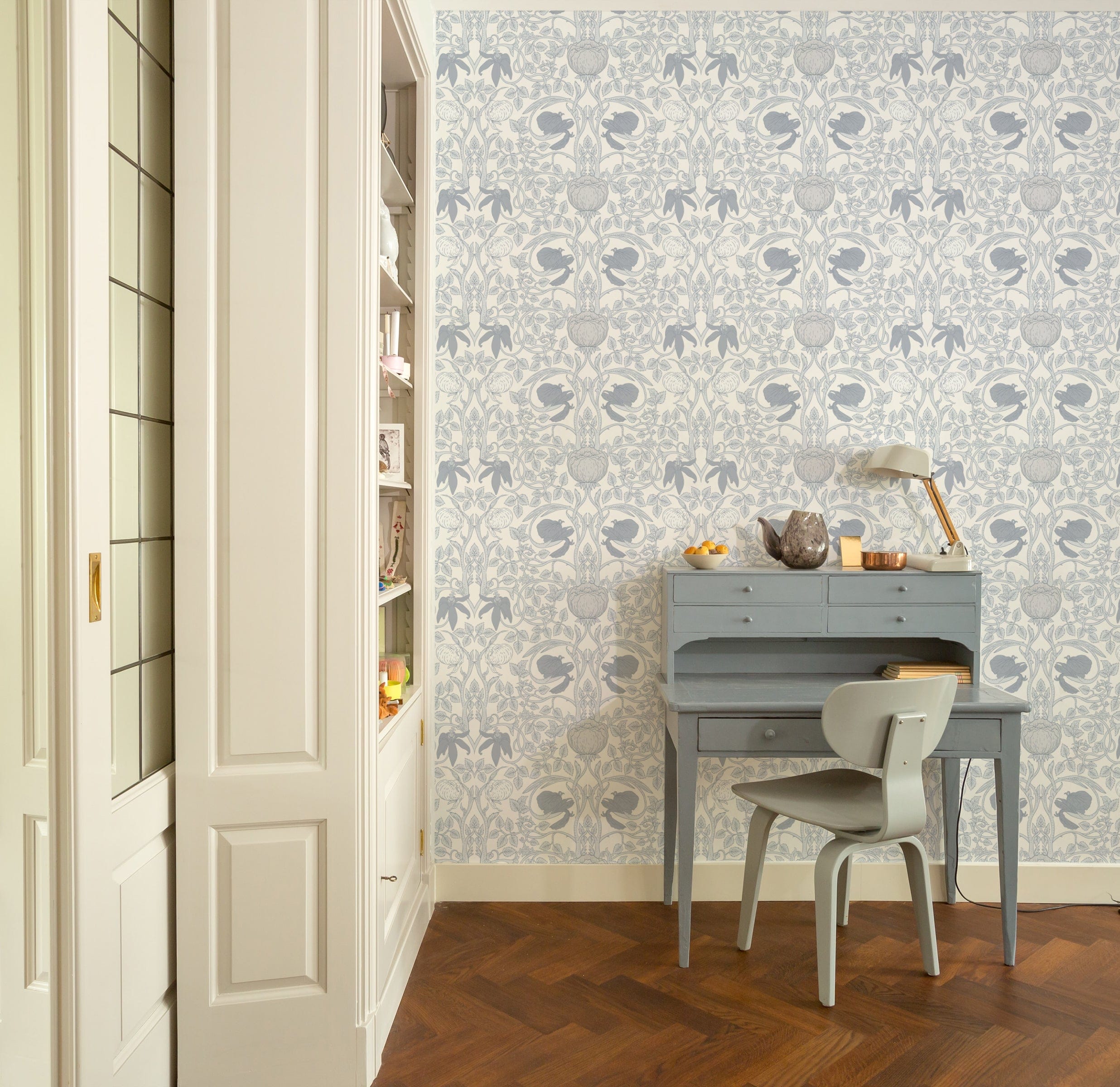 Vintage Floral Damask Wallpaper showcasing an elegant blue floral design in a room with a blue writing desk and chair, wooden flooring, and built-in white shelving.