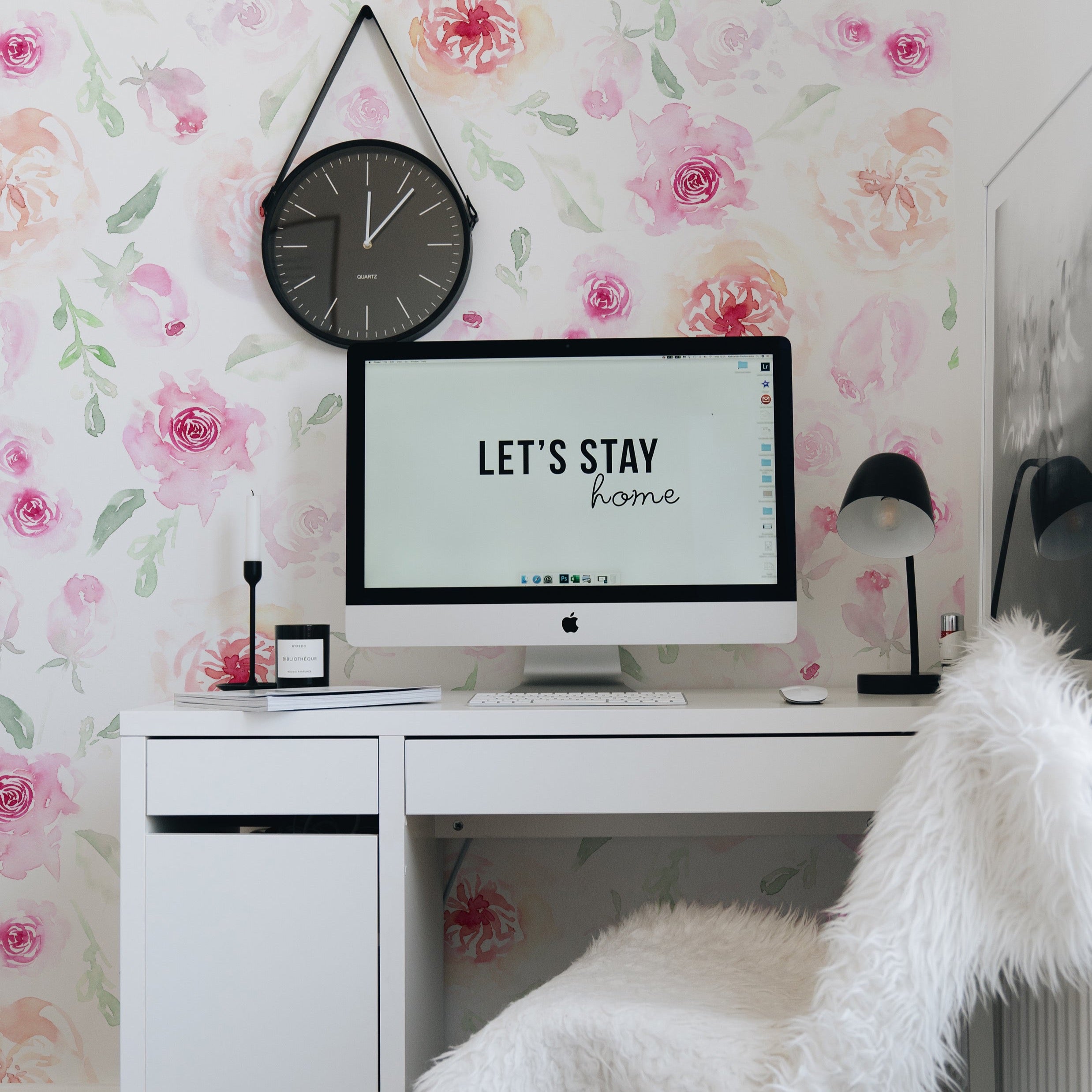 An elegant workspace is brought to life with the 'Pink Watercolour Floral Wallpaper', where rosy blooms surround a sleek white desk, complemented by modern accessories and a statement wall clock, infusing creativity and charm into the decor