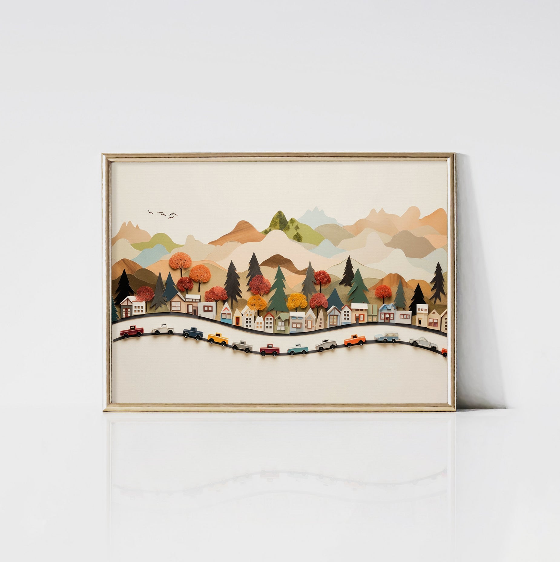 An art print encased in a sleek gold frame, depicting a charming village with colorful cars on a sinuous road, set against a picturesque landscape of hills and mountains. The gold frame adds a touch of elegance to the playful artwork.