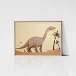 Littlefoot Art Print in a gold frame, depicting a dinosaur on a sandy terrain with palm trees and a bird in the background, adding a touch of elegance to the playful artwork.