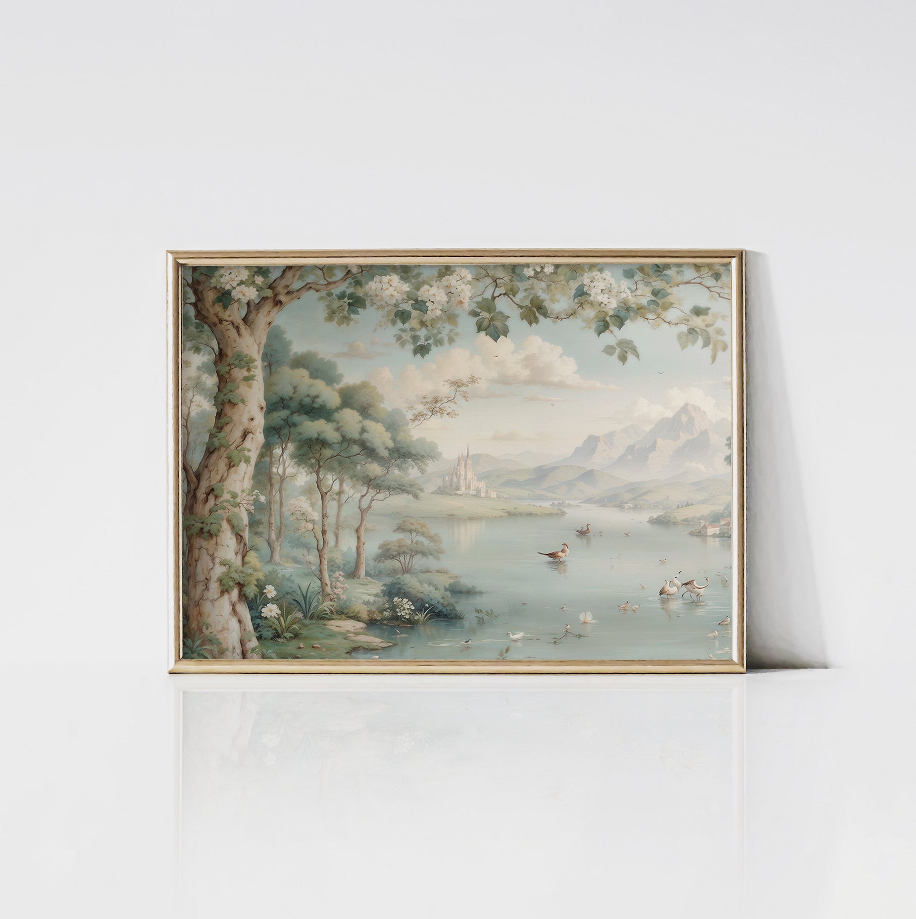 An art print of the tranquil Chamonix Valley framed in gold. The scene features a calm lake surrounded by lush trees, distant mountains, and a castle on the horizon. Birds and ducks enhance the peaceful setting.