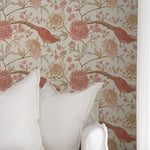 Cozy corner of a room decorated with Peonies and Pheasants Wallpaper, featuring red pheasants and pink peonies against a cream background. The scene includes soft white pillows, creating a tranquil and stylish ambiance