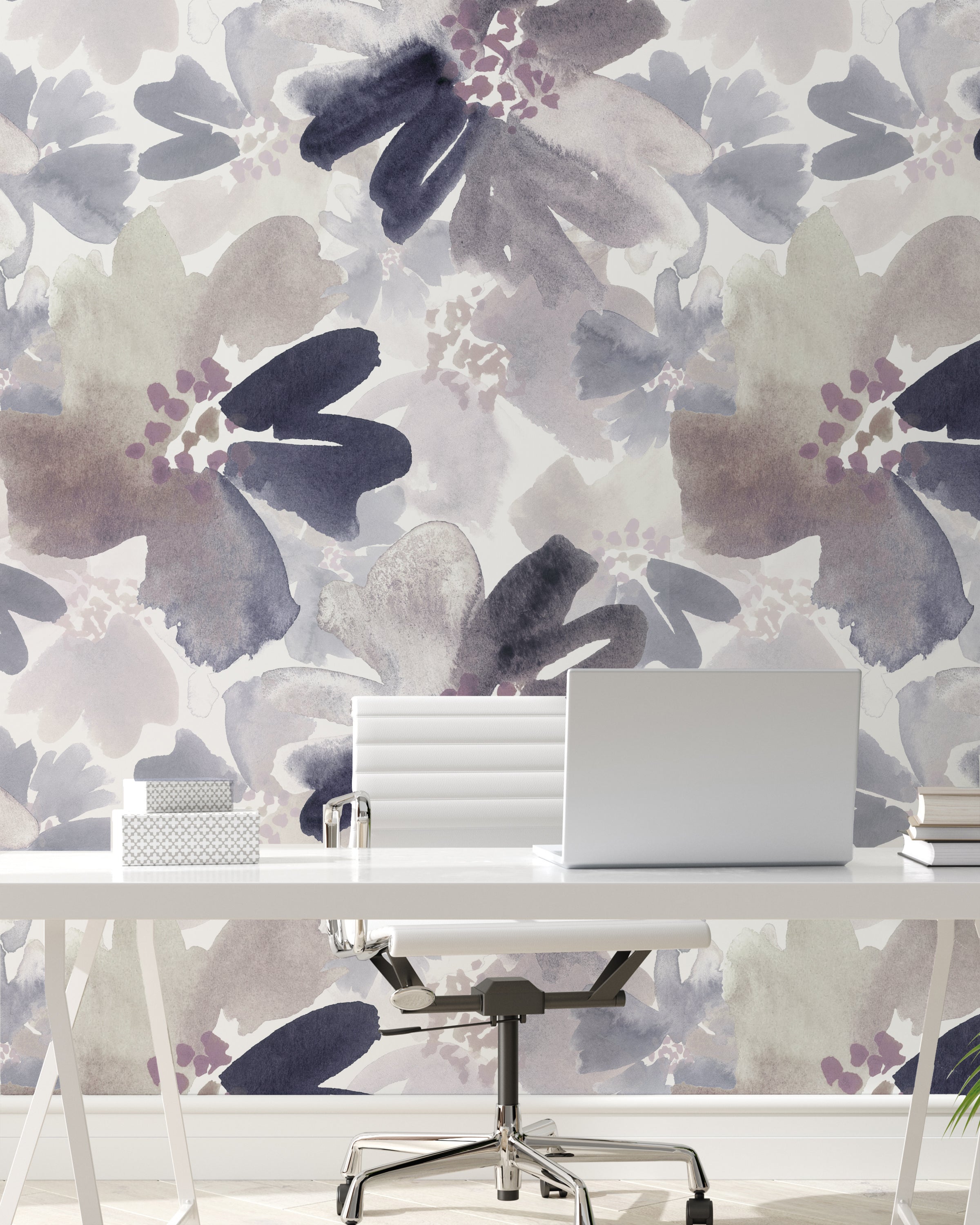 A modern office setting featuring Purple Passion Wallpaper, which showcases large, abstract floral designs in shades of purple, grey, and white. The wallpaper creates a dynamic backdrop for a minimalist white desk with a laptop, enhancing the workspace with a touch of creative flair.