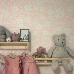 A well-styled shelf against the Flower Power Wallpaper in a children's room. The shelf holds various children's toys and a vintage photo, complemented by the wallpaper's soft floral pattern, enhancing the room's warm and nostalgic feel.
