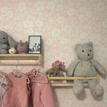 A well-styled shelf against the Flower Power Wallpaper in a children's room. The shelf holds various children's toys and a vintage photo, complemented by the wallpaper's soft floral pattern, enhancing the room's warm and nostalgic feel.