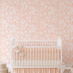 A charming nursery room adorned with the Flower Power Wallpaper in Light Peach, providing a cheerful and soothing environment. The room features a classic white crib, complemented by soft peach bedding and playful children's toys, enhancing the nursery's warm and welcoming atmosphere