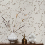 A close-up of 'Charming Floral Wallpaper', showcasing its intricate design of beige flowers connected by thin vines on a creamy background. The pattern radiates a vintage elegance, perfect for a timeless interior.