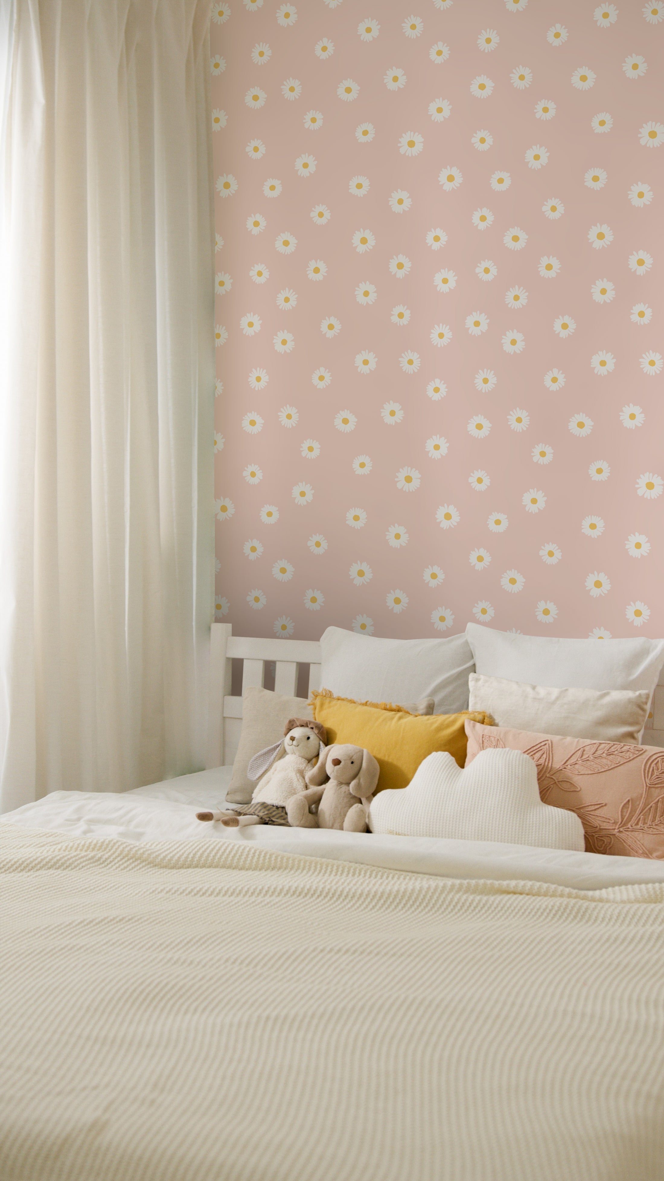  A children’s bedroom featuring the Daisy Daze Wallpaper in a soft peach tone decorated with white daisies. The room includes a bed with white bedding, several plush toys, and cushions, creating a warm and inviting atmosphere. The wallpaper adds a delightful and fresh look to the room, perfect for a child's space.