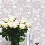 a closer look at the "Whimsical Wings Wallpaper," where a bouquet of cream roses in a clear vase is positioned against the backdrop. The delicate butterflies and floral outlines on the wallpaper add a sophisticated and gentle touch to the decor.