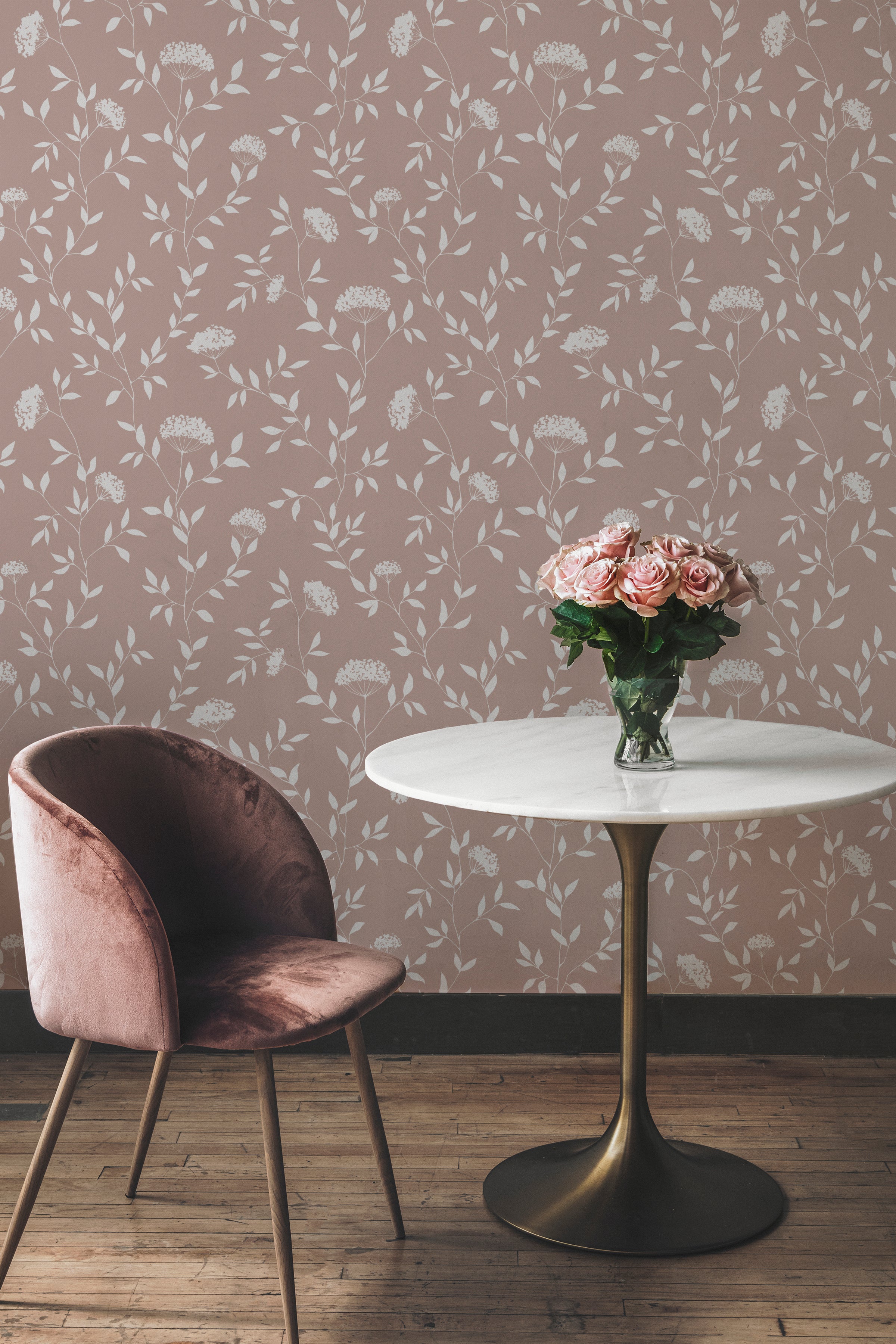 A chic corner of a room featuring the Botanical Elegance wallpaper in taupe with white floral patterns. A velvet pink chair and a round table with a vase of pink roses complement the wallpaper, adding a touch of sophistication.