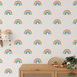 A vibrant playroom corner with Chasing Rainbows wallpaper. The room is accessorized with children's toys and a wooden shelf, emphasizing the wallpaper's fun and youthful charm.