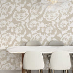 A cozy dining area adorned with Stamped Floral Wallpaper, creating an inviting ambiance with its large, hand-stamped flower motif in a soothing beige palette. The design complements the modern furniture and adds a touch of nature-inspired elegance.