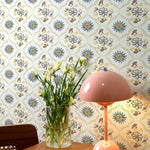 An interior setting with the Spanish Tile Wallpaper in the background enhancing a mid-century modern decor. A pastel pink mushroom lamp sits on a wooden table, alongside a vase with fresh tulips, creating a warm and inviting ambiance