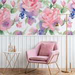 An elegant living area decorated with Mystic Garden Wallpaper, featuring large pink roses and subtle blue flowers. The room includes a plush pink armchair and a gold and white side table, creating a sophisticated and calming space perfect for relaxation