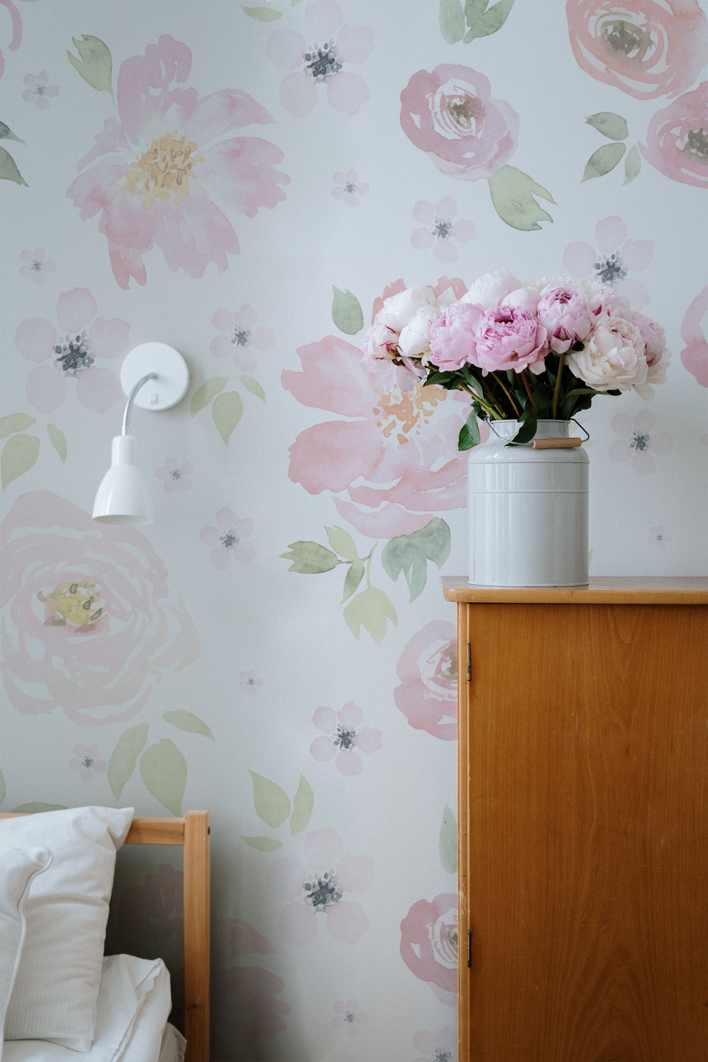 A corner of a bedroom with natural wood furniture, where a vase of fresh pink peonies on a nightstand complements the 'Gentle Blossom Wallpaper', enhancing the room's romantic and serene ambiance.