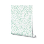 A roll of wallpaper displaying a mint green leafy pattern on a white background. The small leaves are arranged in a vertical pattern, providing a refreshing and soothing look.