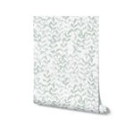 A roll of wallpaper featuring a light green leafy pattern on a white background. The simple and elegant design consists of small leaves arranged in a vertical pattern, creating a fresh and natural look.