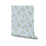 Roll of Simple Floral Wallpaper - 25" showcasing the delicate pattern of small white flowers and green leaves on a soft blue background. The design is perfect for adding a touch of whimsy and charm to any room.