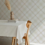 Royal Tartan Plaid Wallpaper displayed in a dining room setting. The beige and cream tartan pattern brings a cozy and stylish atmosphere to the space, enhanced by a rustic vase with dried pampas grass on a white tablecloth-covered dining table