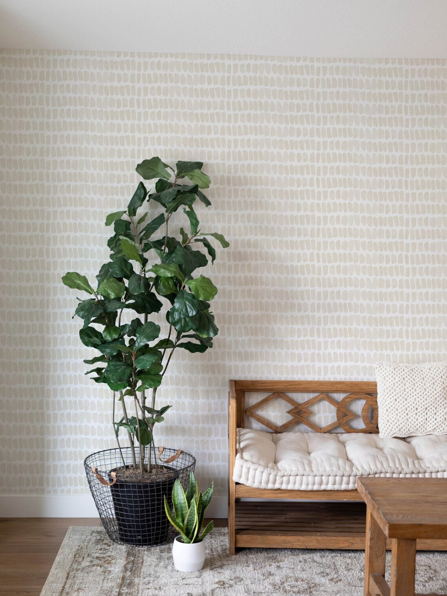 An interior setting where the Ecru Watercolour Dots Wallpaper is used to decorate a cozy corner. The wallpaper's subtle design complements the natural wooden furniture and the greenery of indoor plants, creating a relaxed and organic ambiance in the room. The image shows how the wallpaper can enhance a living space without overwhelming it.