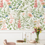 Elegant dining area enhanced by Watercolour Floral and Leaf Wallpaper II, with pastel floral patterns providing a soft backdrop to a modern table setting with pink chairs and a marble table.