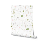 An image of the rolled Watercolour Floral Wallpaper in Blush Pink, revealing the subtle and soft design of the paper. The wallpaper features a pattern of pink flowers, delicate green leaves, and thin branches, all rendered in a gentle watercolor style that gives the impression of a hand-painted artwork. This wallpaper roll is indicative of the light and airy feel the pattern will bring to a space when applied to a wall.