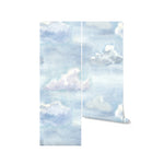 A roll of the "Watercolour Cloud and Skies" wallpaper partially unfurled, showing off the gentle gradient of blues and whites that capture the essence of a calm, cloudy sky. The watercolor effect adds a creative and soothing element to any room.