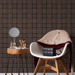 An elegant interior setting where Dark Plaid Wallpaper - Black serves as a backdrop, exuding a classic, sophisticated charm. The scene includes a stylish mid-century modern chair draped with a knit sweater and a purse, a side table with personal items and a round mirror, creating a personal vanity space.